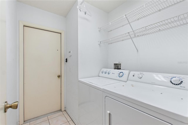 clothes washing area featuring washer and clothes dryer and light tile patterned flooring