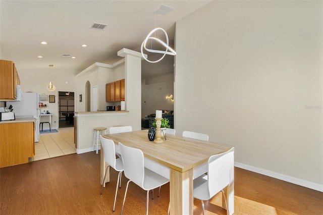 dining room featuring vaulted ceiling and light hardwood / wood-style flooring