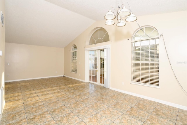 empty room featuring a healthy amount of sunlight, vaulted ceiling, and an inviting chandelier