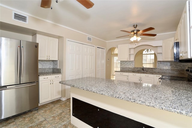 kitchen with white cabinetry, kitchen peninsula, appliances with stainless steel finishes, and tasteful backsplash