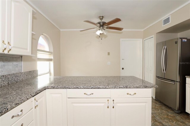 kitchen featuring white cabinetry, light stone counters, stainless steel refrigerator, and ornamental molding