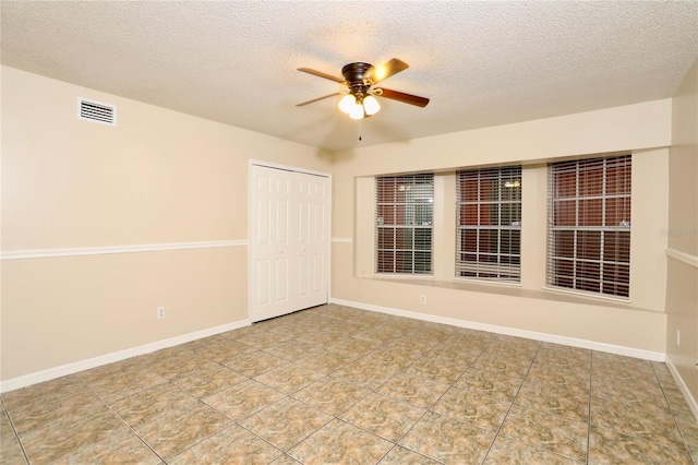 tiled spare room with a textured ceiling and ceiling fan