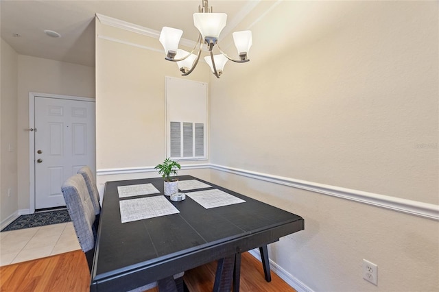 dining room with ornamental molding, hardwood / wood-style floors, and an inviting chandelier