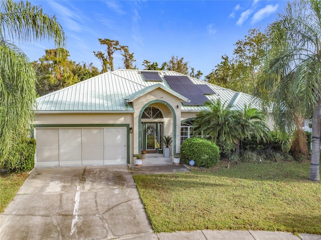 view of front of property with a garage, solar panels, and a front lawn