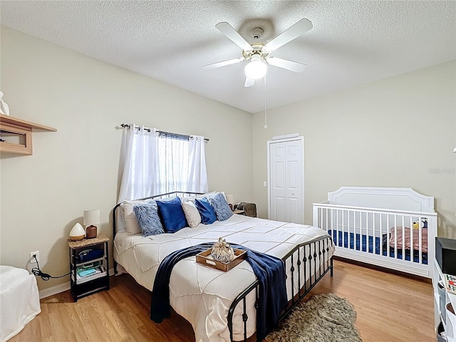 bedroom featuring a closet, a textured ceiling, ceiling fan, and light hardwood / wood-style flooring