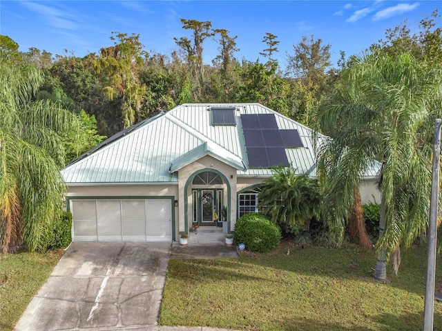 view of front of property with a garage, a front yard, and solar panels