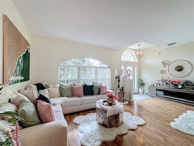 living room with an inviting chandelier, hardwood / wood-style flooring, and a textured ceiling