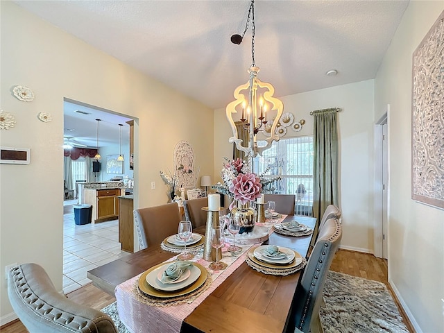 dining area featuring light wood-type flooring, a notable chandelier, and a textured ceiling