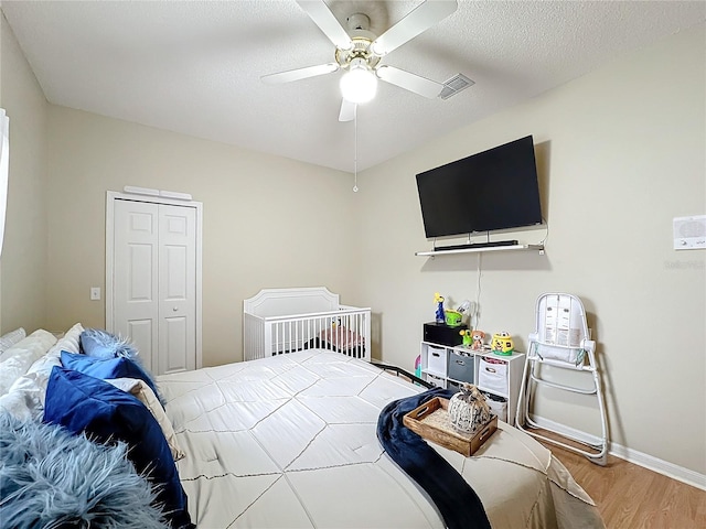 bedroom featuring hardwood / wood-style flooring, a textured ceiling, ceiling fan, and a closet