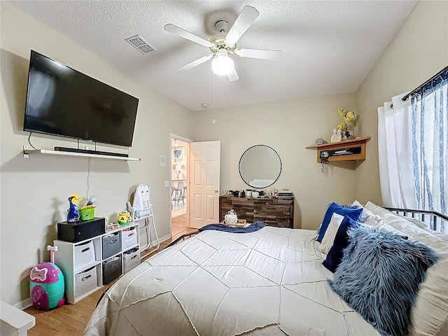 bedroom featuring a textured ceiling, light wood-type flooring, and ceiling fan