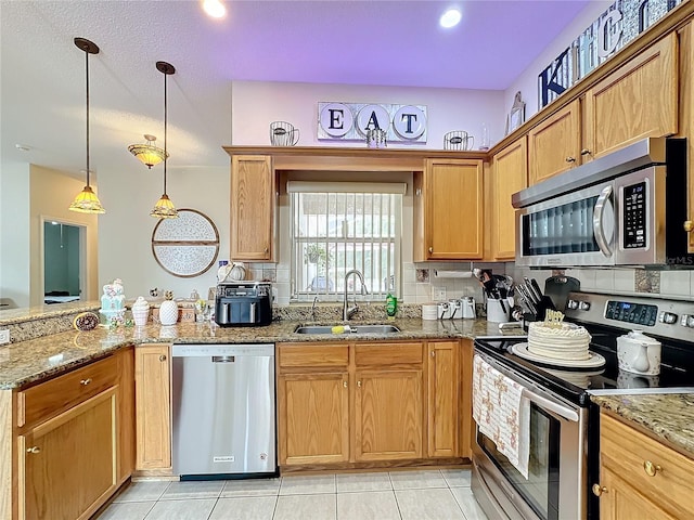 kitchen featuring light stone counters, sink, tasteful backsplash, pendant lighting, and appliances with stainless steel finishes