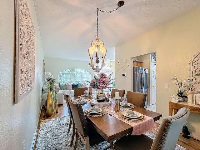 dining room featuring a textured ceiling, an inviting chandelier, and light hardwood / wood-style flooring