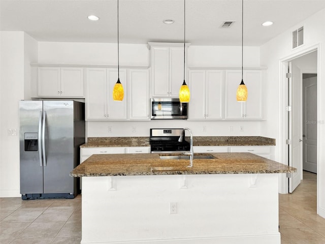 kitchen featuring dark stone counters, white cabinetry, appliances with stainless steel finishes, and a kitchen island with sink