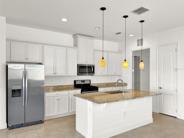 kitchen with stainless steel appliances, a center island with sink, white cabinetry, stone counters, and pendant lighting