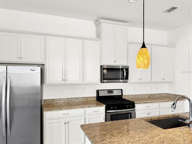 kitchen featuring hanging light fixtures, white cabinets, sink, and stainless steel appliances