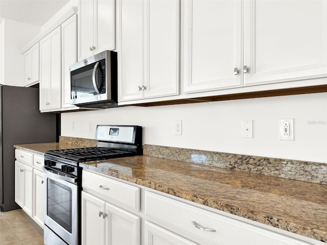 kitchen featuring white cabinetry, appliances with stainless steel finishes, light tile patterned floors, and stone countertops