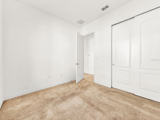 unfurnished bedroom featuring light colored carpet and a closet