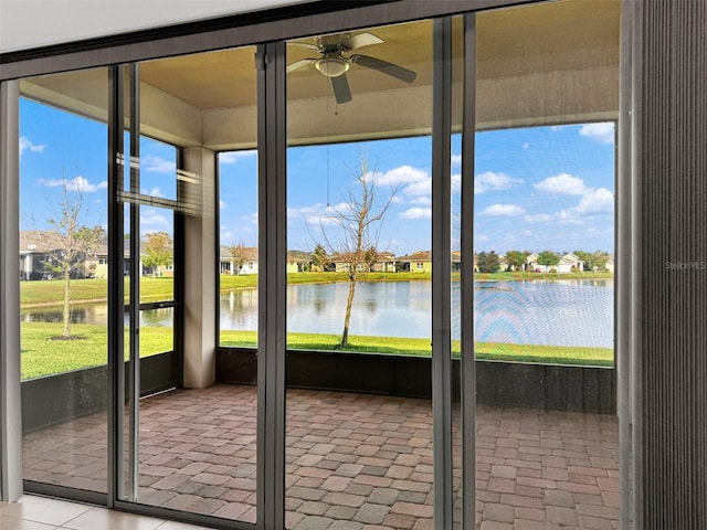 unfurnished sunroom with ceiling fan, a healthy amount of sunlight, and a water view