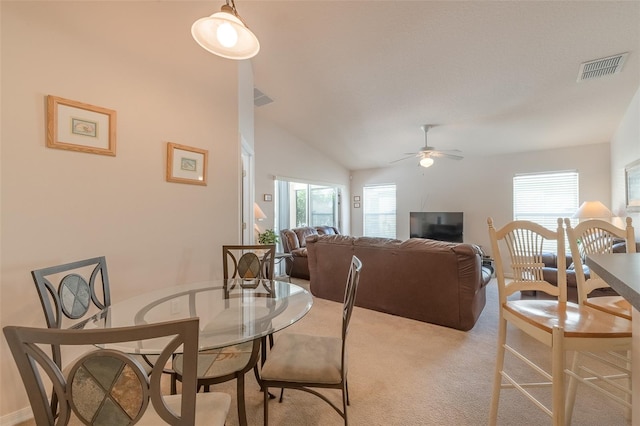 carpeted dining room with ceiling fan, a healthy amount of sunlight, and lofted ceiling