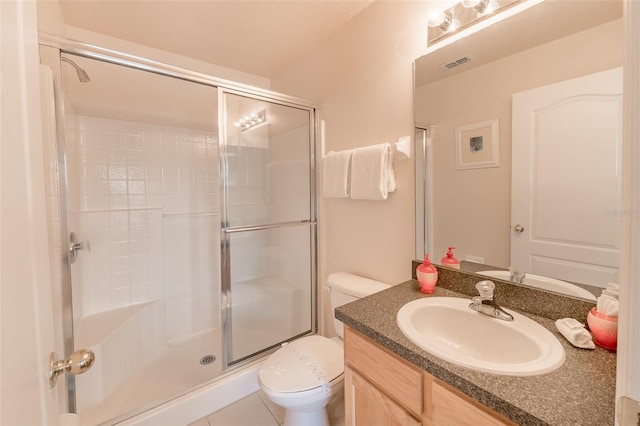 bathroom featuring toilet, vanity, tile patterned flooring, and a shower with shower door