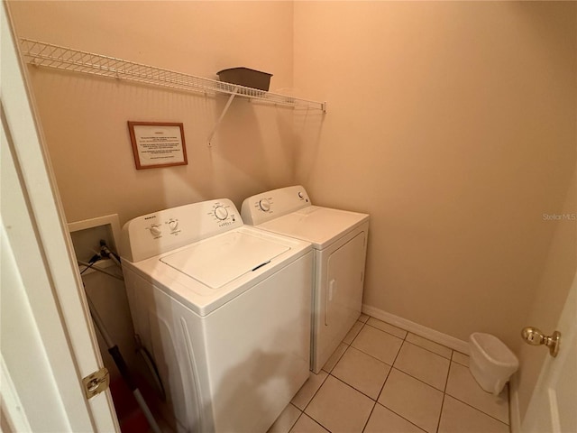 clothes washing area featuring light tile patterned flooring and separate washer and dryer