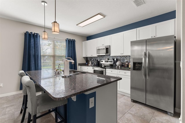 kitchen with appliances with stainless steel finishes, backsplash, sink, decorative light fixtures, and white cabinets