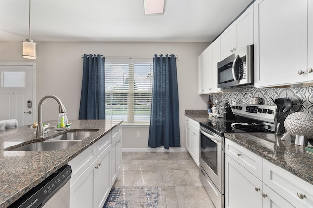 kitchen with dark stone counters, hanging light fixtures, sink, appliances with stainless steel finishes, and white cabinetry