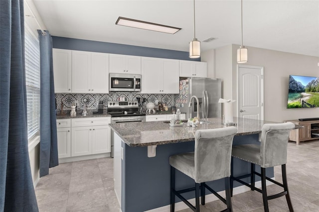 kitchen featuring white cabinetry, an island with sink, hanging light fixtures, and appliances with stainless steel finishes