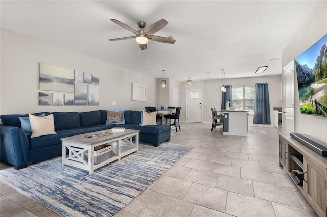 tiled living room with ceiling fan and a textured ceiling