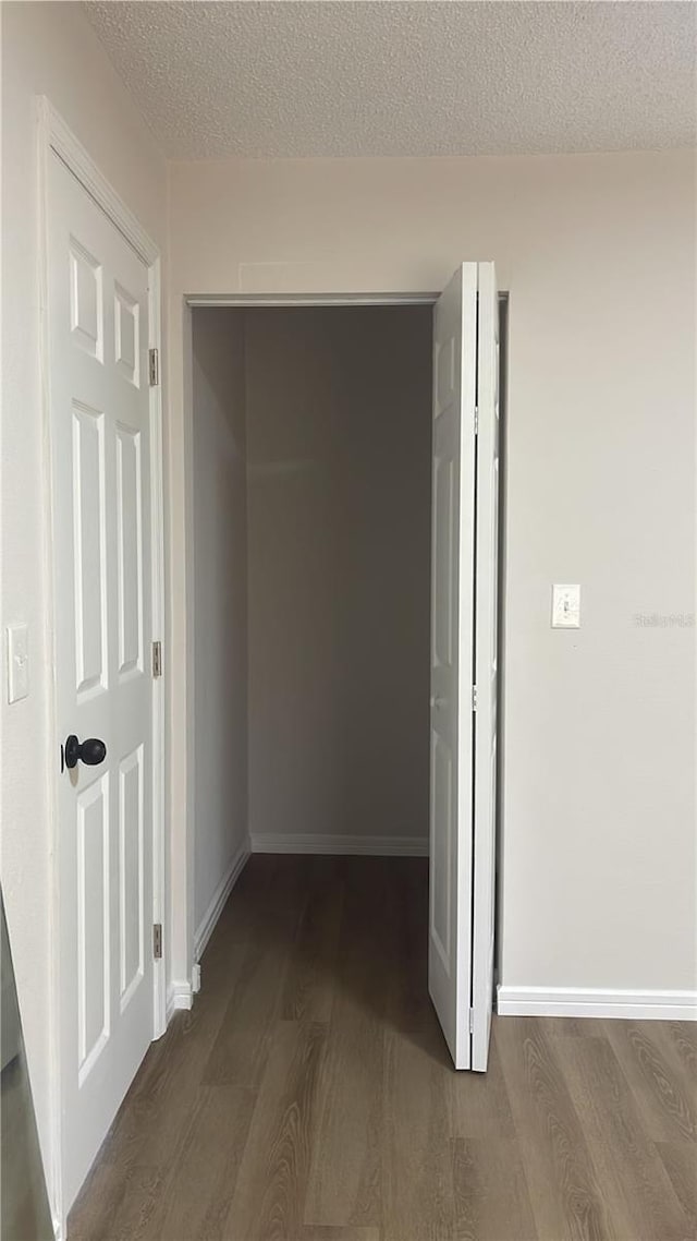 hall with a textured ceiling and dark wood-type flooring