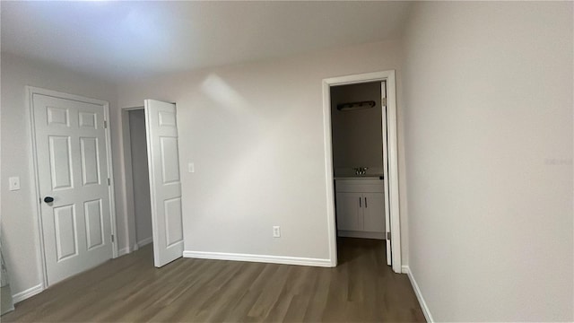 unfurnished bedroom featuring ensuite bathroom and dark hardwood / wood-style floors