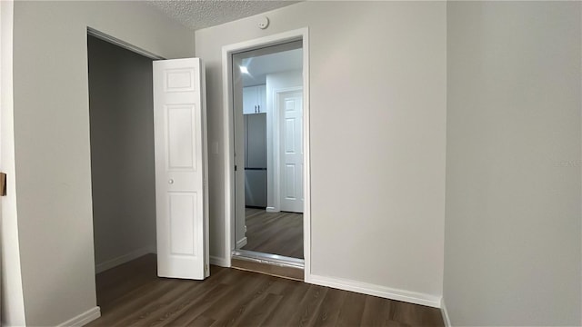 corridor with dark hardwood / wood-style floors and a textured ceiling