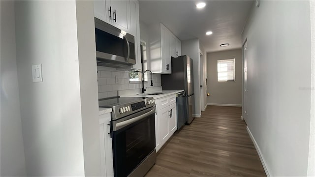 kitchen featuring dark wood-type flooring, sink, decorative backsplash, appliances with stainless steel finishes, and white cabinetry