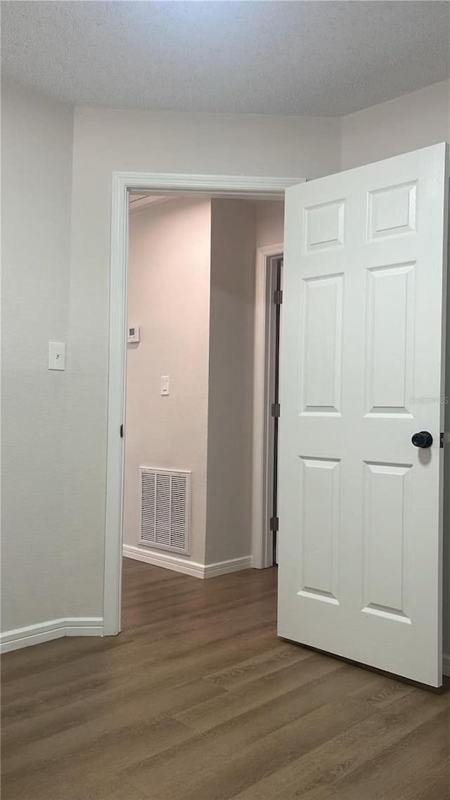 hallway featuring dark hardwood / wood-style flooring and a textured ceiling