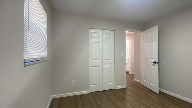 unfurnished bedroom with dark hardwood / wood-style floors and a closet