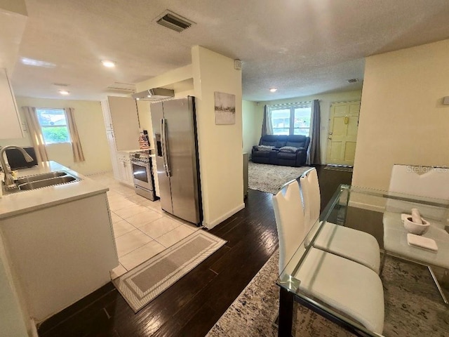 kitchen featuring light wood-type flooring, appliances with stainless steel finishes, a wealth of natural light, sink, and white cabinets