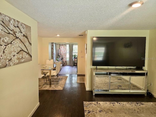 living room with a textured ceiling and dark hardwood / wood-style floors