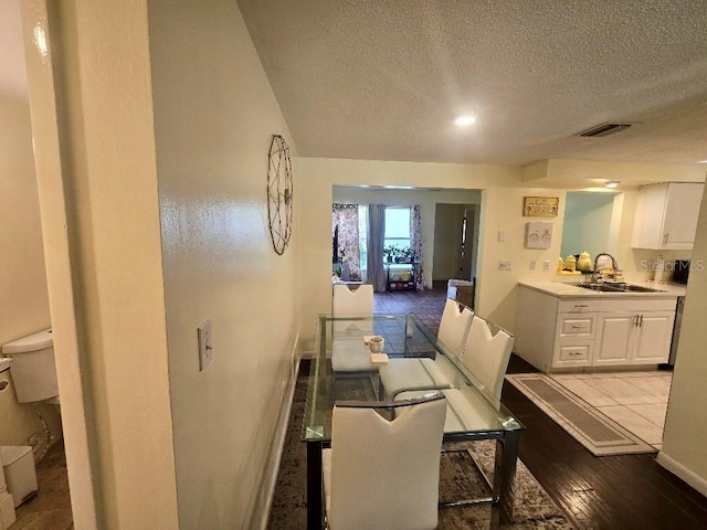 dining room featuring a textured ceiling, sink, and light hardwood / wood-style flooring