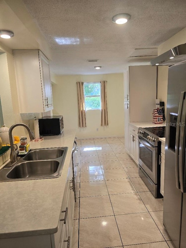 kitchen with white cabinets, a textured ceiling, sink, light tile patterned floors, and appliances with stainless steel finishes