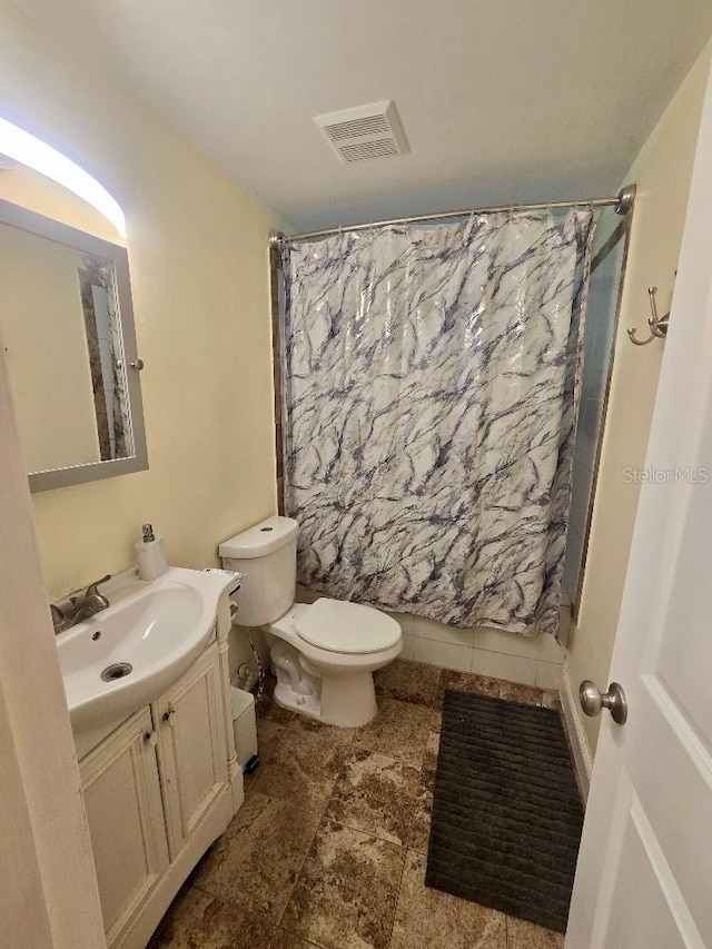 bathroom with walk in shower, vanity, and toilet