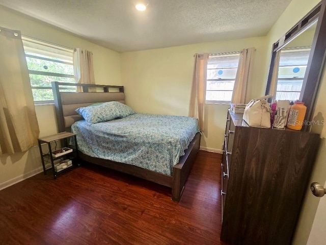 bedroom with a textured ceiling, multiple windows, and dark hardwood / wood-style floors