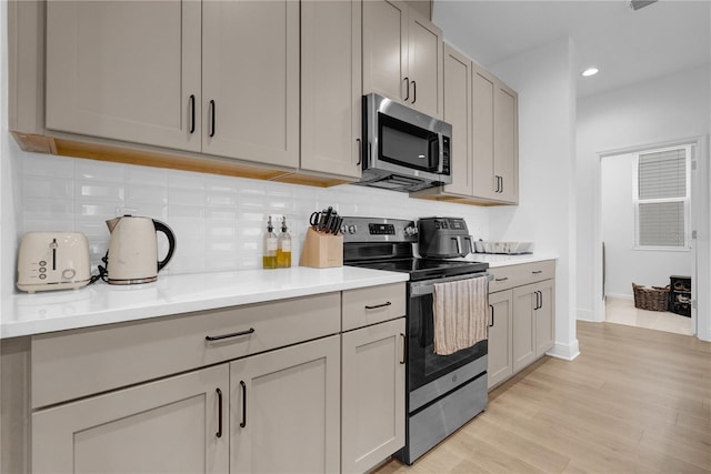 14442 Noto Ave, Clermont, FL 34714 - kitchen featuring appliances with stainless steel finishes, tasteful backsplash, light wood-type flooring, recessed lighting, and light countertops