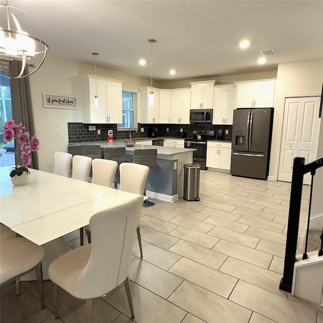 kitchen with a kitchen bar, white cabinetry, pendant lighting, and appliances with stainless steel finishes