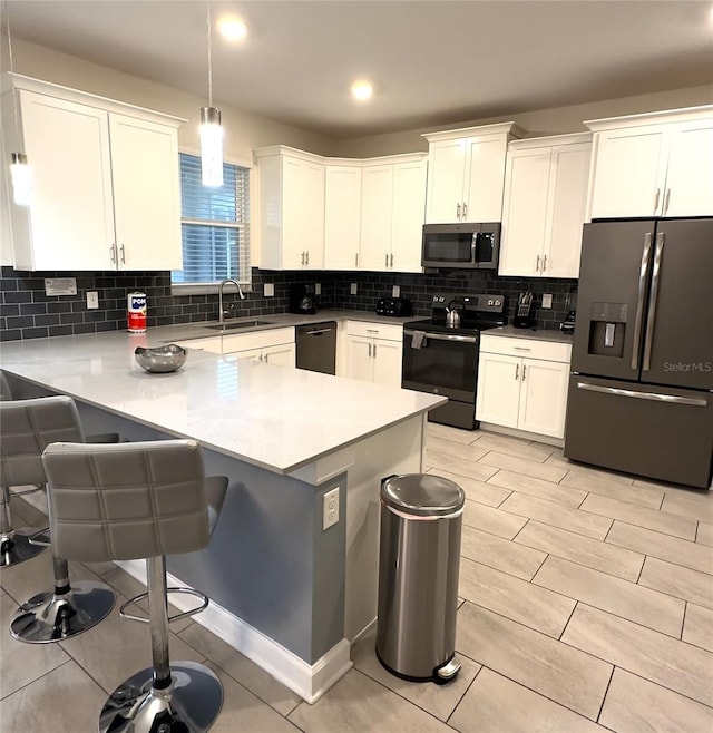 kitchen featuring kitchen peninsula, white cabinetry, decorative light fixtures, and appliances with stainless steel finishes