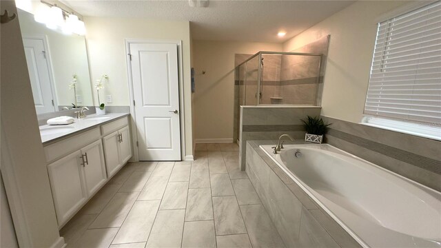 bathroom featuring plus walk in shower, a textured ceiling, and vanity