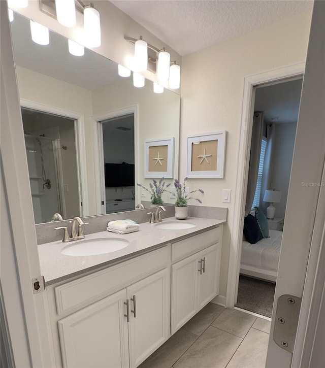 bathroom with tile patterned floors, vanity, an enclosed shower, and a textured ceiling