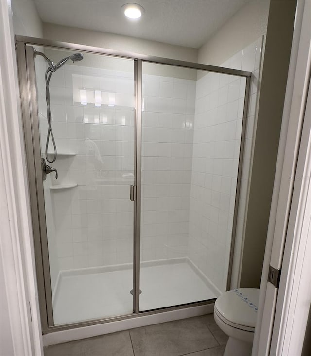 bathroom with tile patterned floors, toilet, and walk in shower