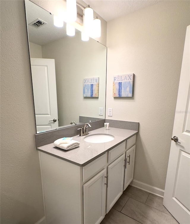 bathroom with tile patterned flooring, a textured ceiling, and vanity