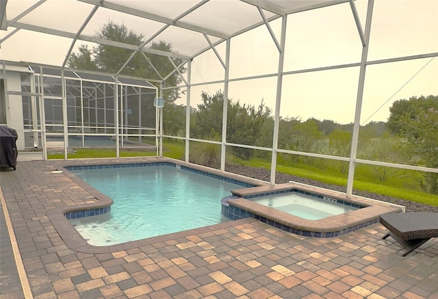 view of pool with an in ground hot tub, glass enclosure, and a patio area