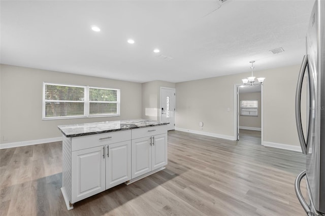 kitchen featuring an inviting chandelier, light wood-type flooring, a center island, white cabinets, and pendant lighting